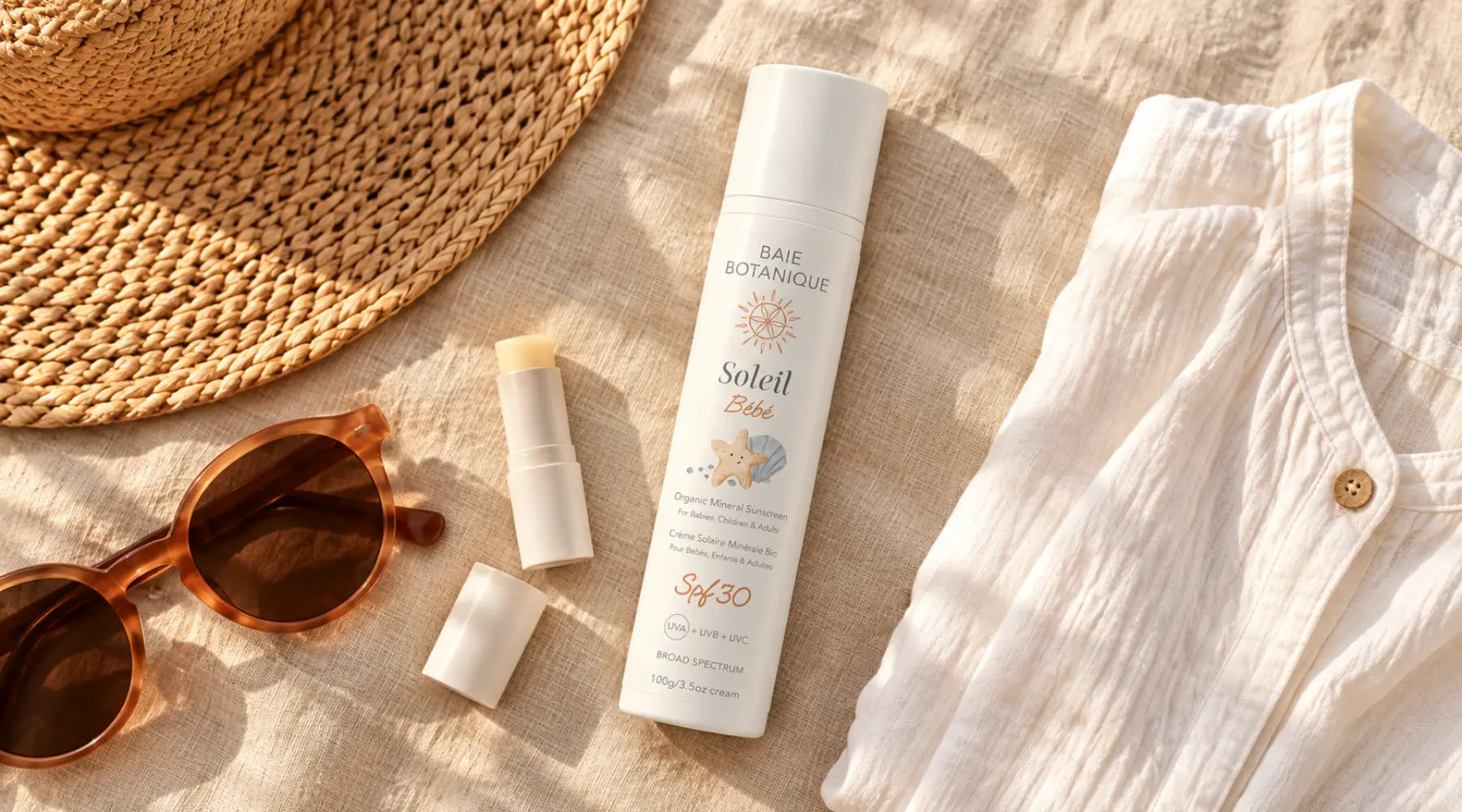 A travel flatlay on warm linen featuring sunscreen, sunglasses, lip SPF, a beach cover-up and a folded map in amber morning light.
